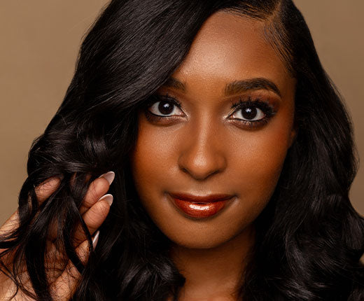 Woman with long relaxed black hair styled in soft waves, showcasing smooth, shiny hair with Design Essentials haircare.